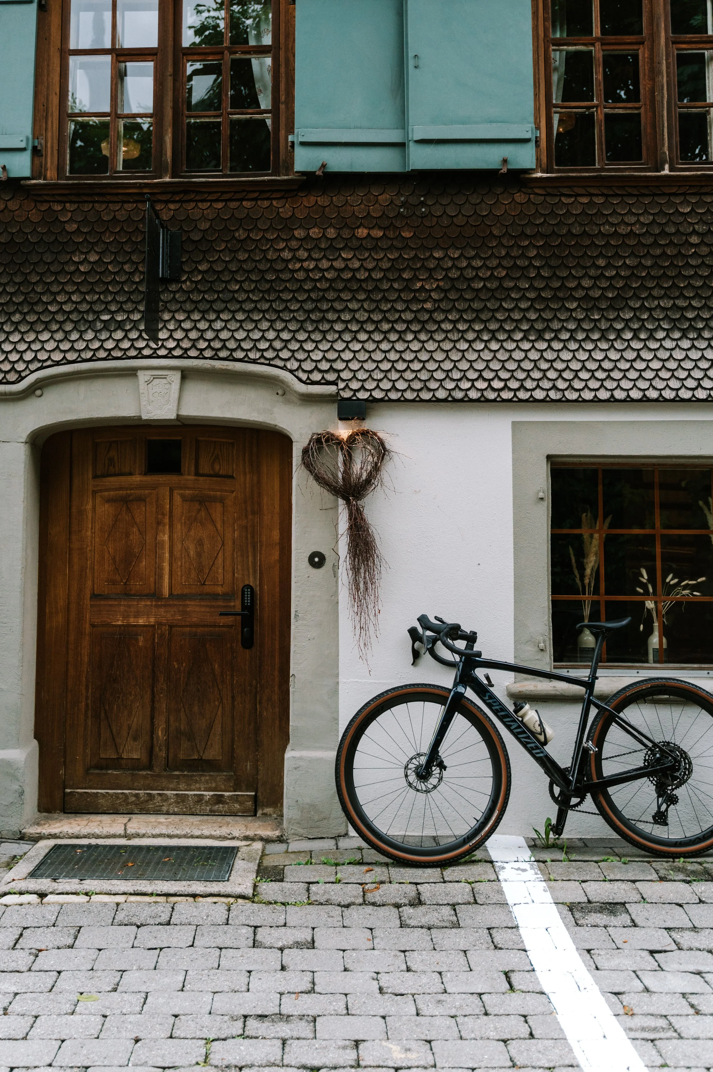 Hauswand mit Holzfenstern, Holztür, Fahrrad und Herzdeko an der Hauswand.