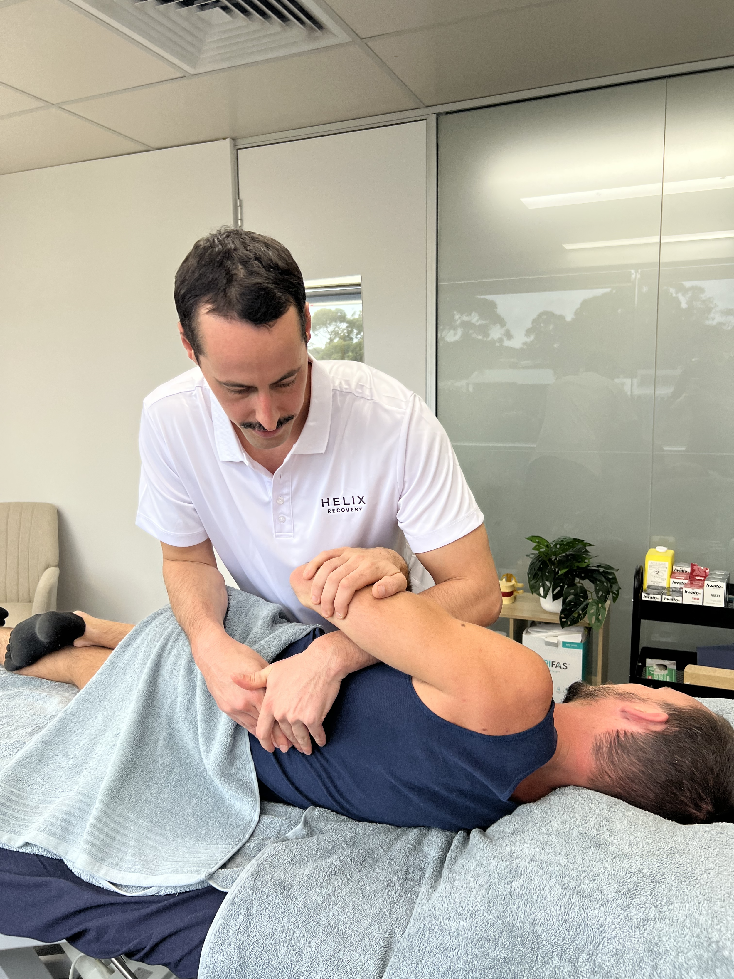 A man receiving osteopathic treatment from a therapist in a medical office.
