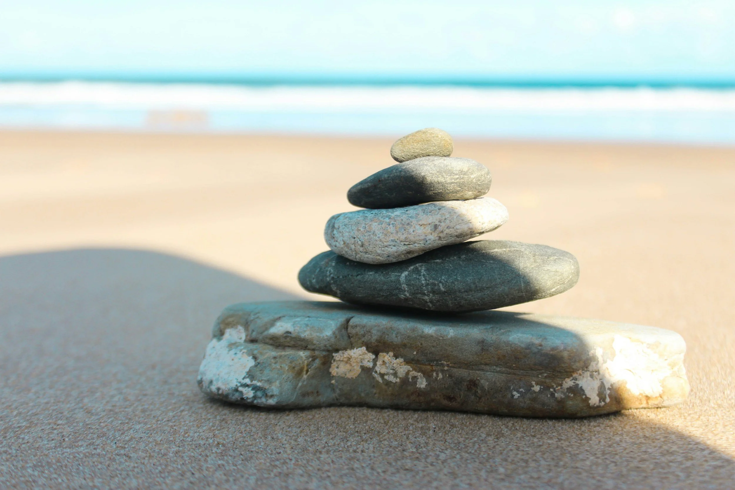 Reiki energy healing session in Rockhampton, supporting relaxation, stress reduction, emotional wellbeing, energy balance, grounding, and overall wellness, symbolised by stacked stones on a peaceful beach.