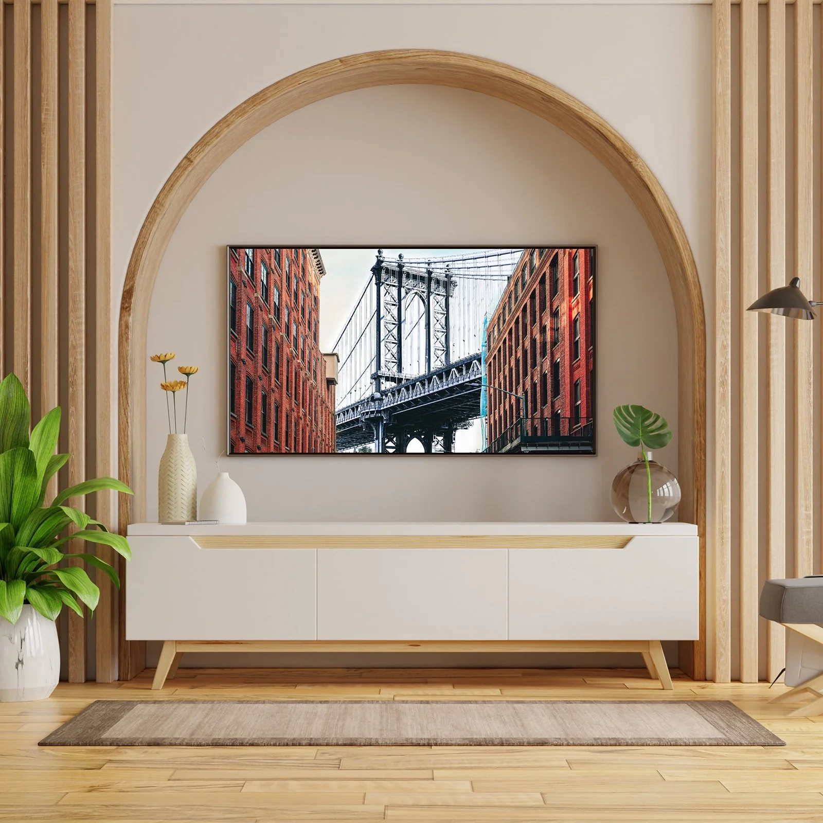 Living room with a mounted flat-screen TV displaying a bridge between two red brick buildings, framed by an arched wall and wooden accents, with potted plants and vases on a white console.