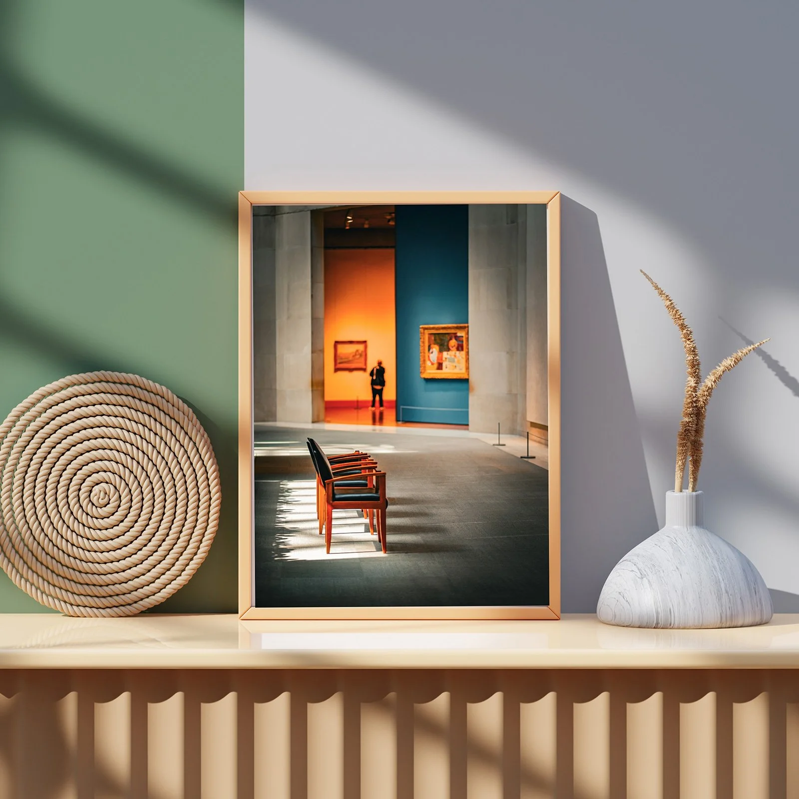 A framed photograph on a shelf shows the inside of an art gallery with paintings on the walls, chairs, and a person viewing the artwork.