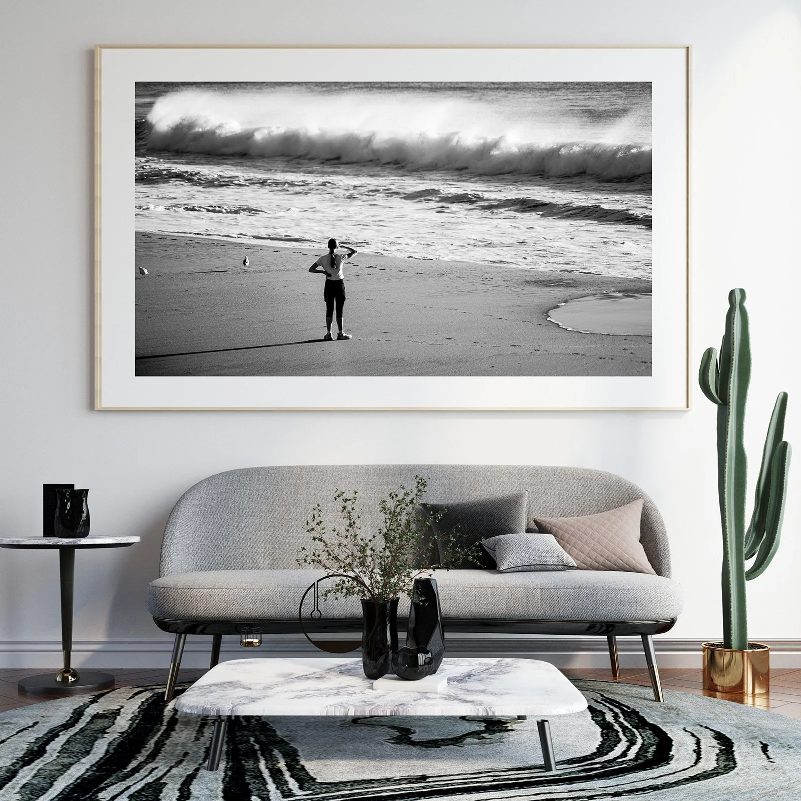 Black and white photograph of a woman standing on a beach, looking out at the ocean waves.