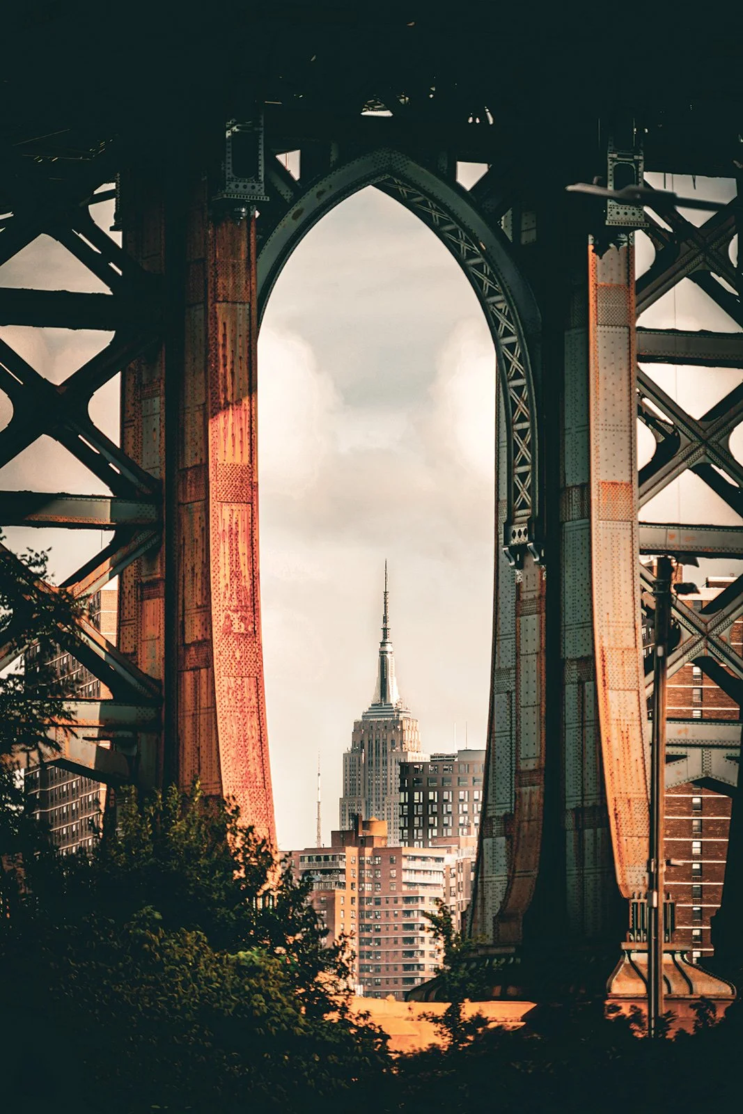 View of the Empire State Building through a large, industrial steel archway.