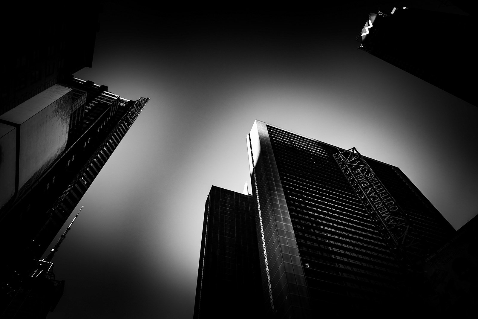 Black and white photo of tall skyscrapers looking up from below.