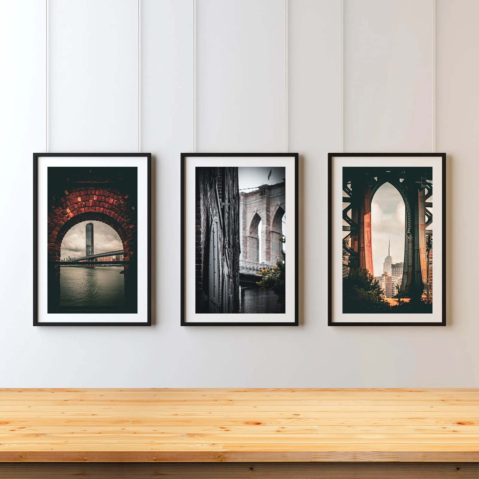 Three framed photographs of cityscapes displayed on a wall in an art gallery.