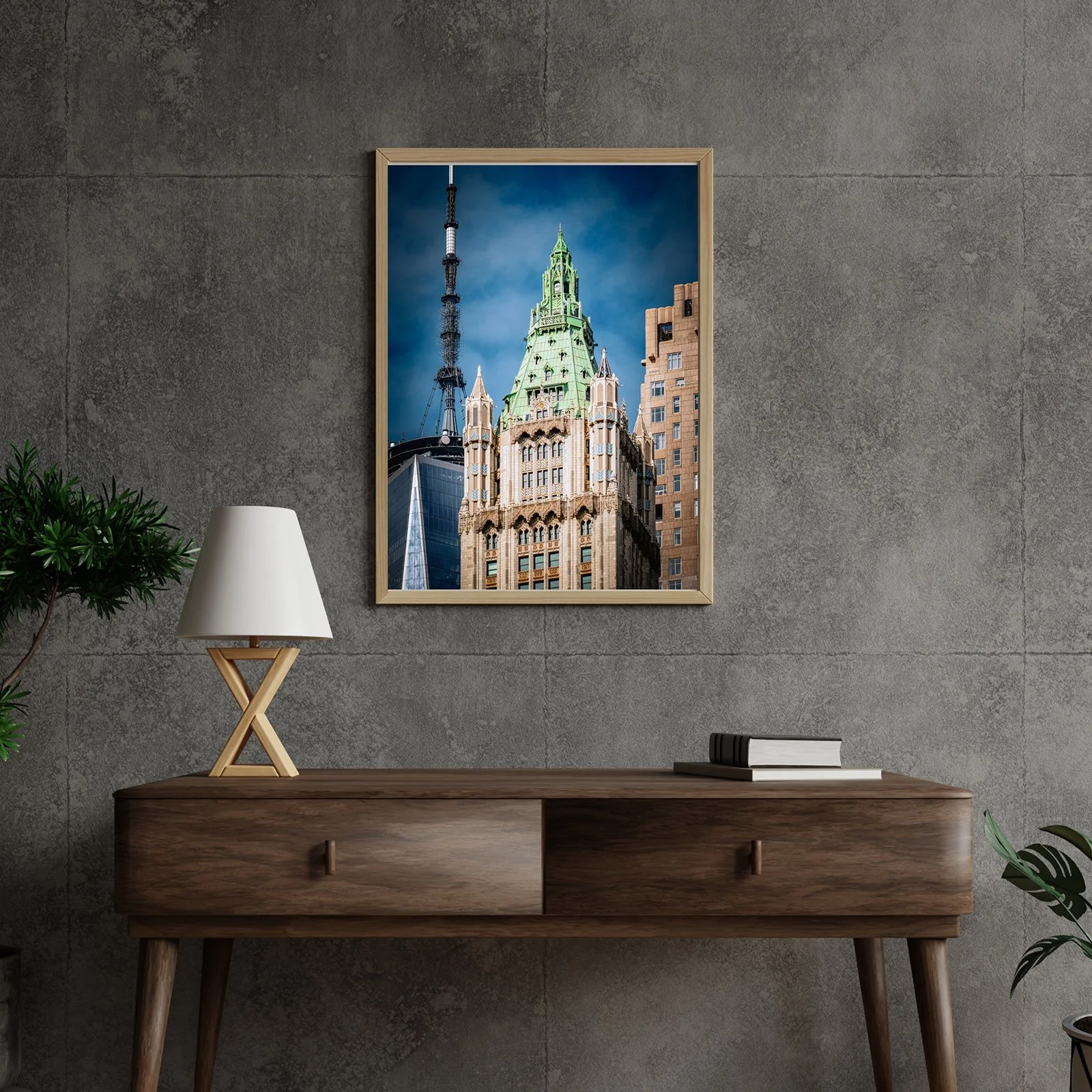 A framed photograph of a skyscraper with a green pointed roof and a tall antenna, mounted on a concrete wall in a modern interior space.