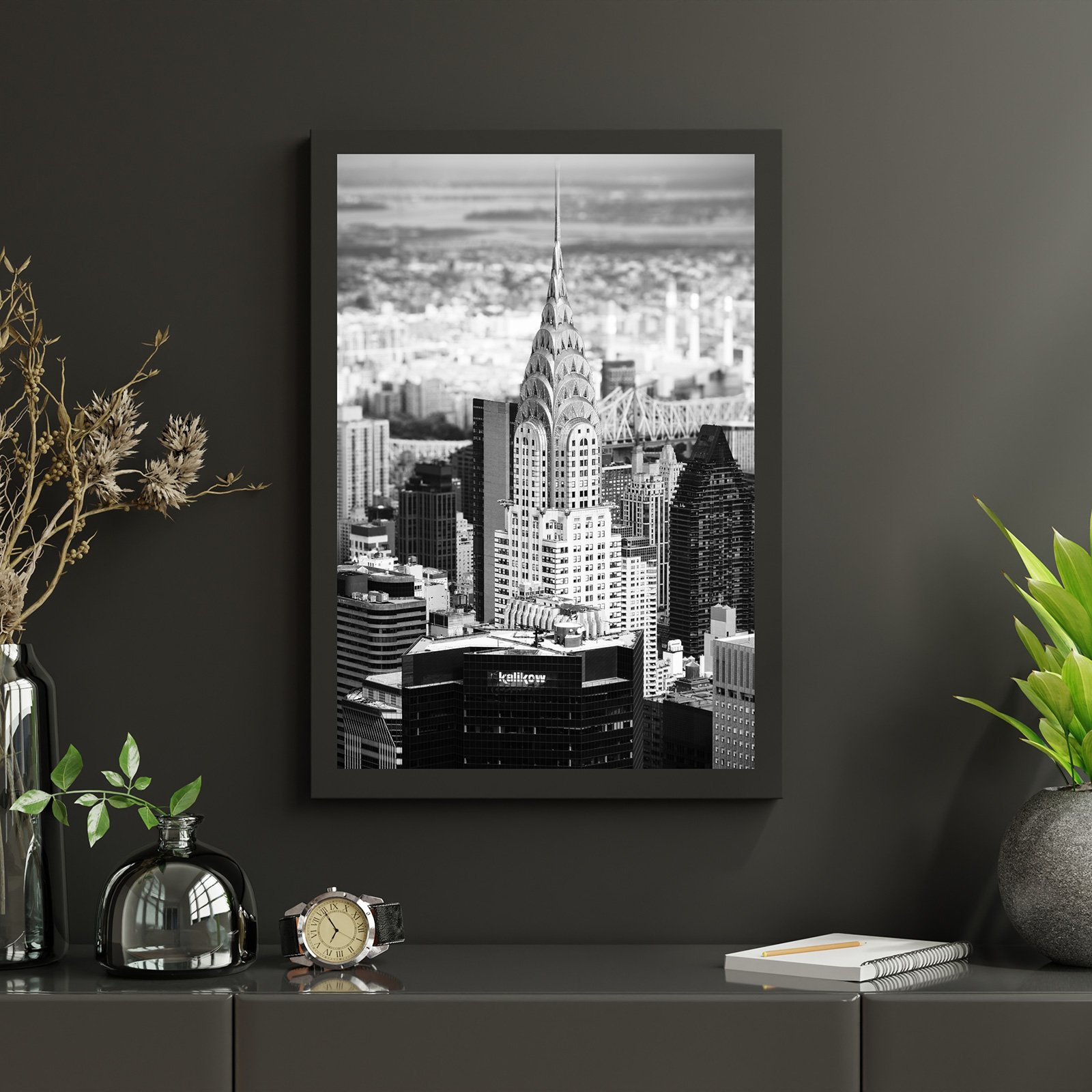 Black and white photograph of the Chrysler Building in New York City, framed and hung on a dark wall.