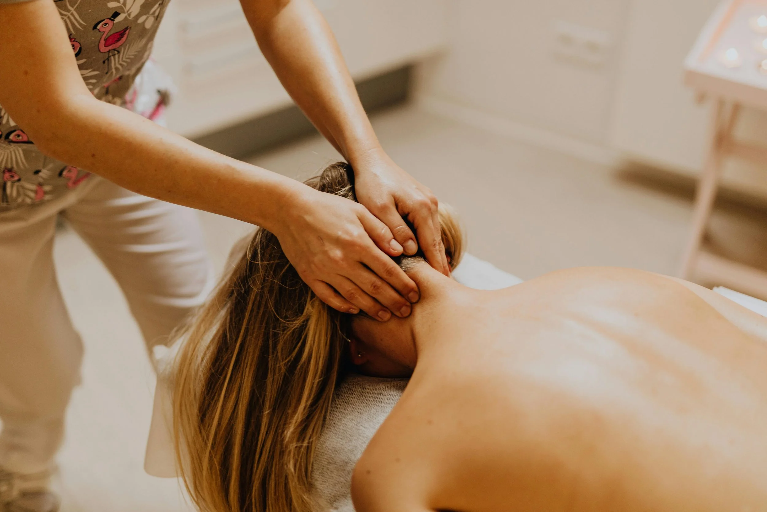 Person receiving a neck massage from a massage therapist in a wellness setting.