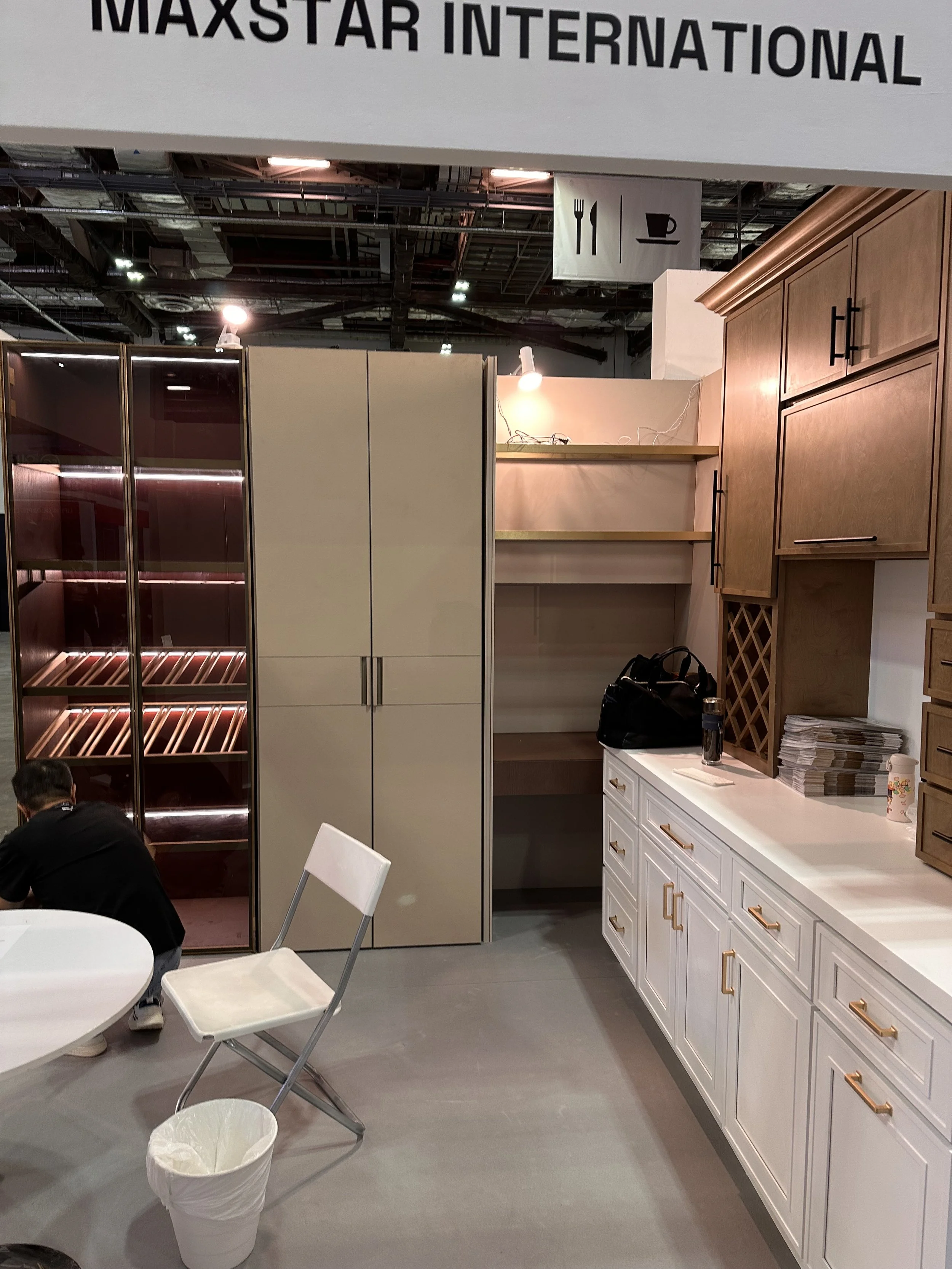 Interior of a furniture store with display cabinets and cabinets, a white table with white chairs, and miscellaneous items on the cabinets.