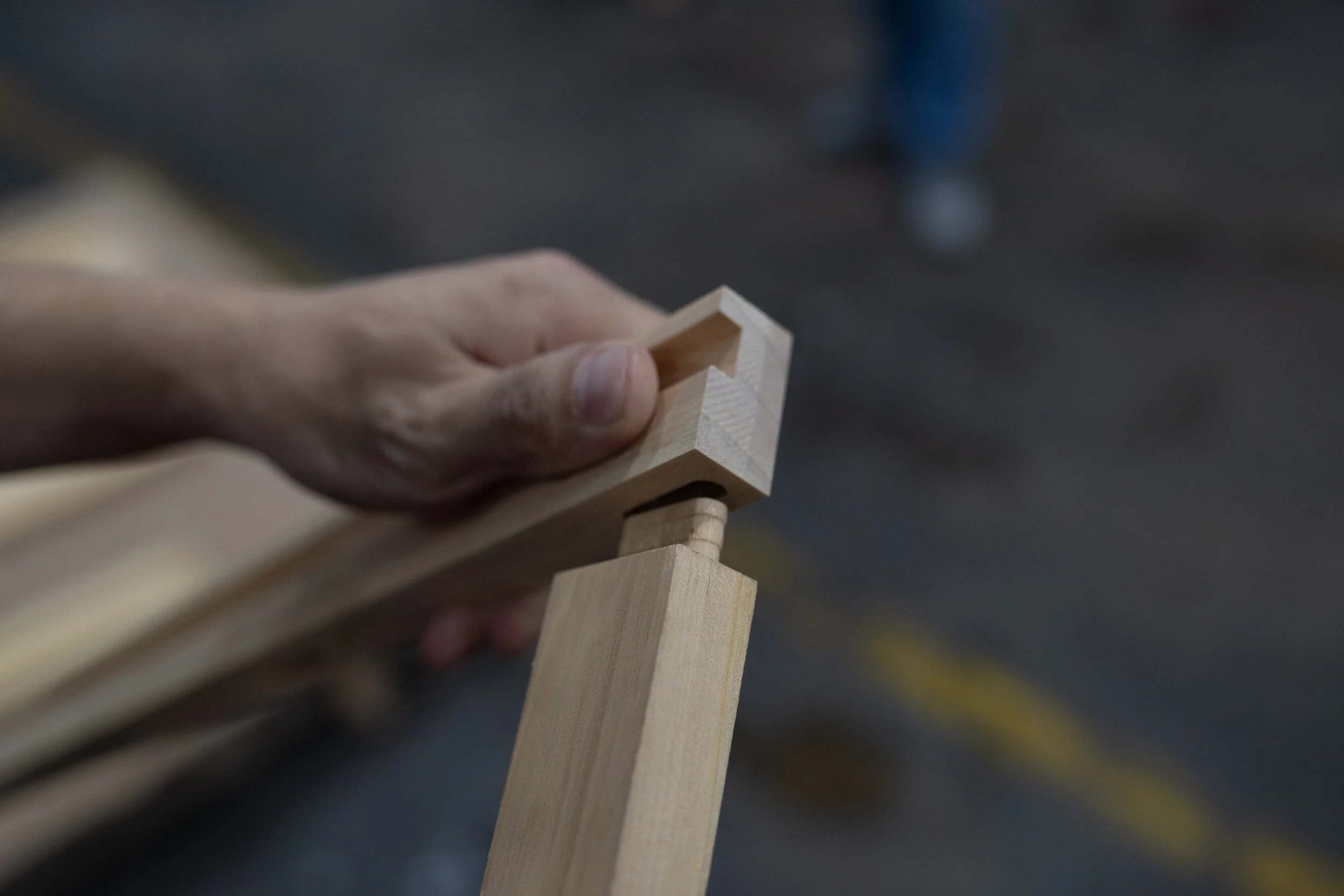 Close-up of a hand holding a small wooden block with other wooden blocks stacked in the background.
