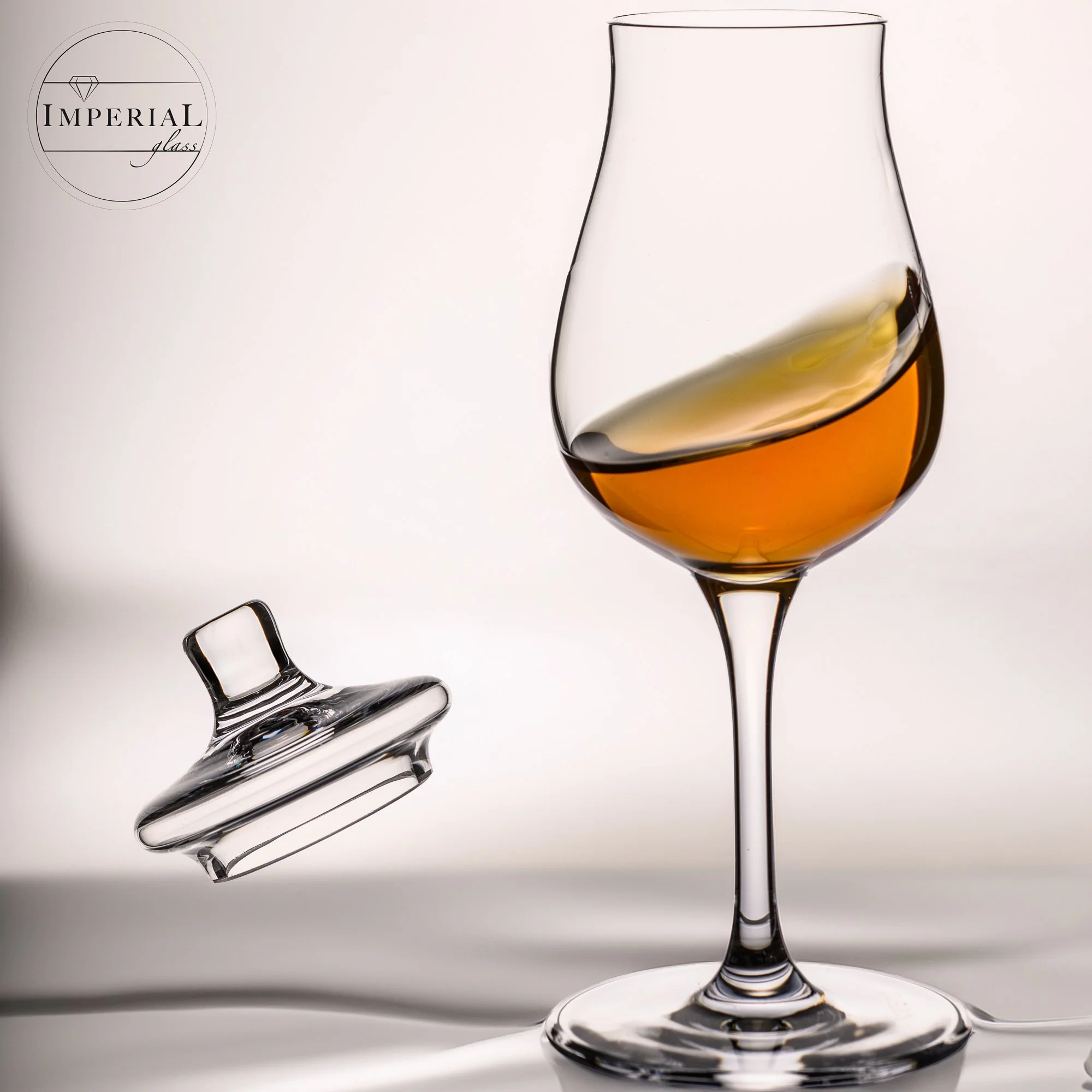 Ein Weinglas mit goldenem Wein, daneben ein zerbrochener Weinkelch aus Glas.