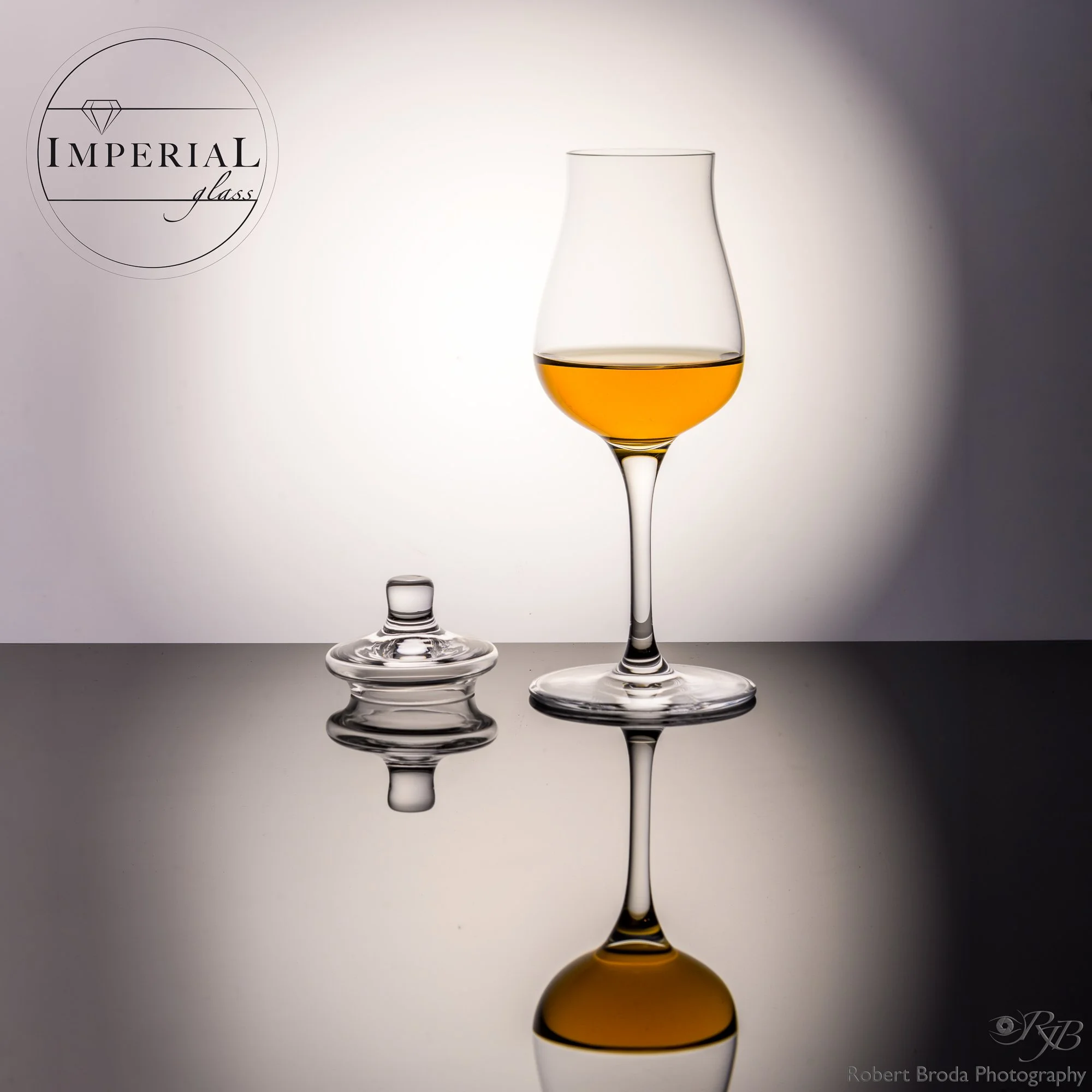 Ein stilisiertes Bild von drei Weingläsern, die nacheinander gestapelt sind und jeweils mit einer dunklen Flüssigkeit gefüllt sind. Im linken oberen Bereich befindet sich ein Logo mit einem Diamanten und dem Text 'Imperial Glass'. Unten rechts steht 