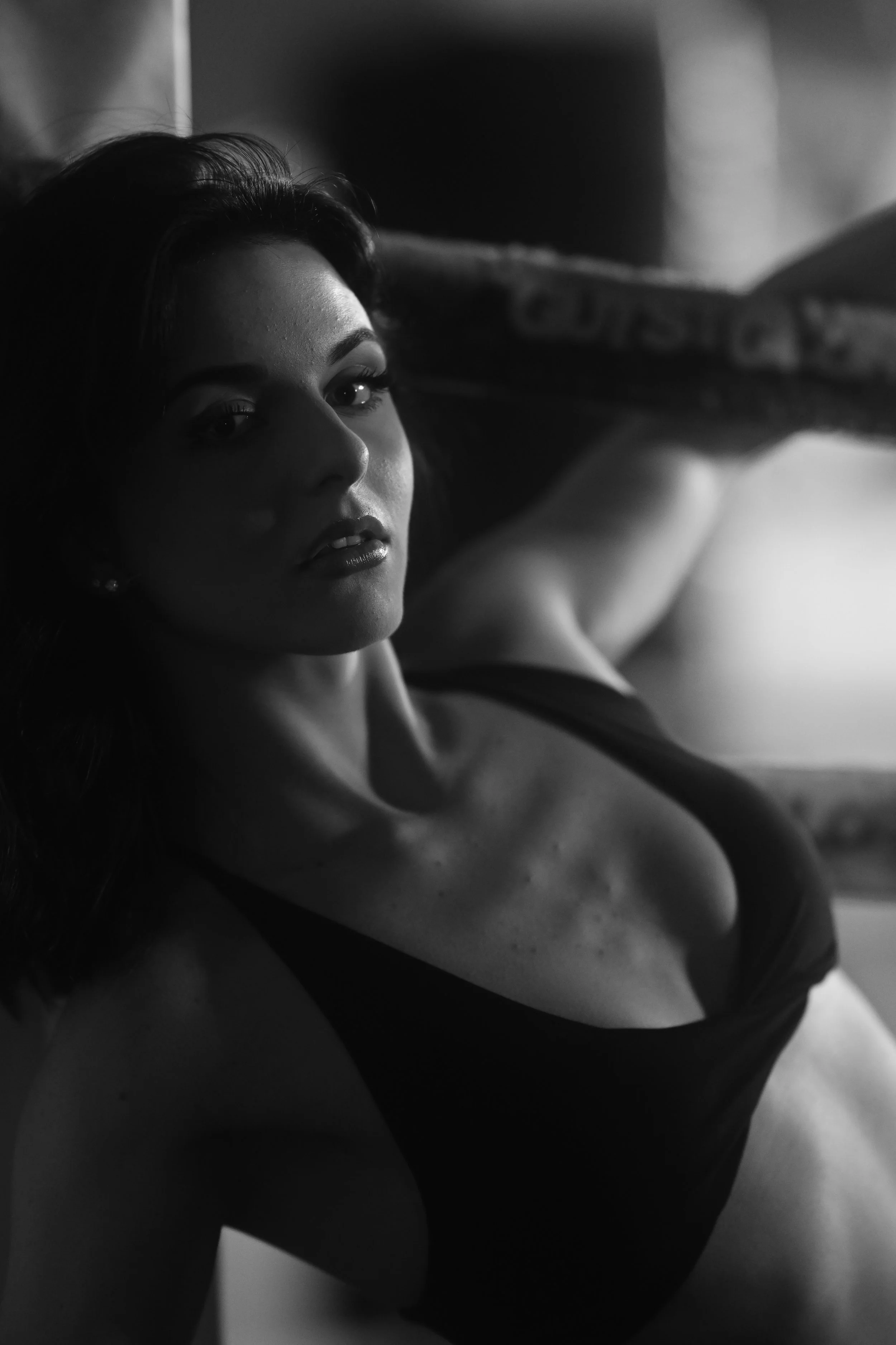 Schwarzes und weißes Porträt einer Frau, die auf dem Bett liegt, mit Blick in die Kamera, im Schwarz-Weiß-Filter