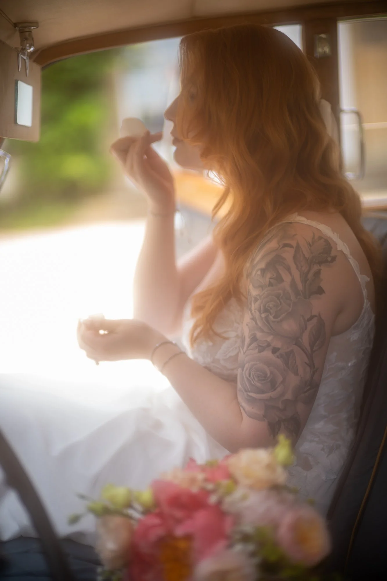 Eine rote-haired Frau mit Tattoo auf Arm beim Schminken vor einem Spiegel.