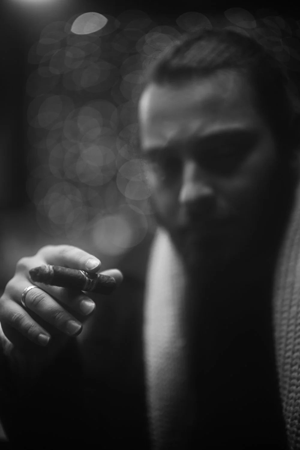 Schwarz-Weiß-Foto einer Person mit Sonnenbrille, die auf eine Zigarre oder Zigarette im Hand hält.