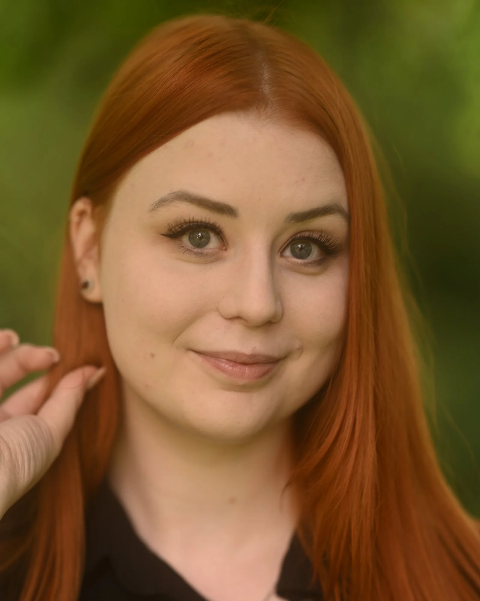 Nahaufnahme eines lachenden Mädchens mit roten Haaren, das die Hand nahe dem Gesicht hält.