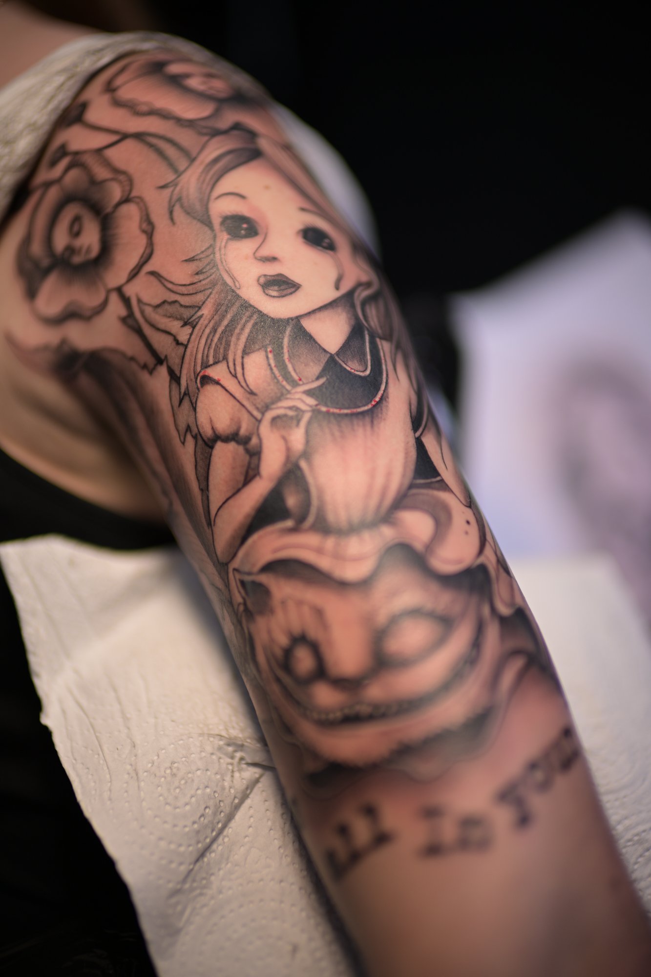 Nahaufnahme eines Tattoos auf einem Arm, das eine stilisierte Mädchenfigur mit langen Haaren und Blumen zeigt.