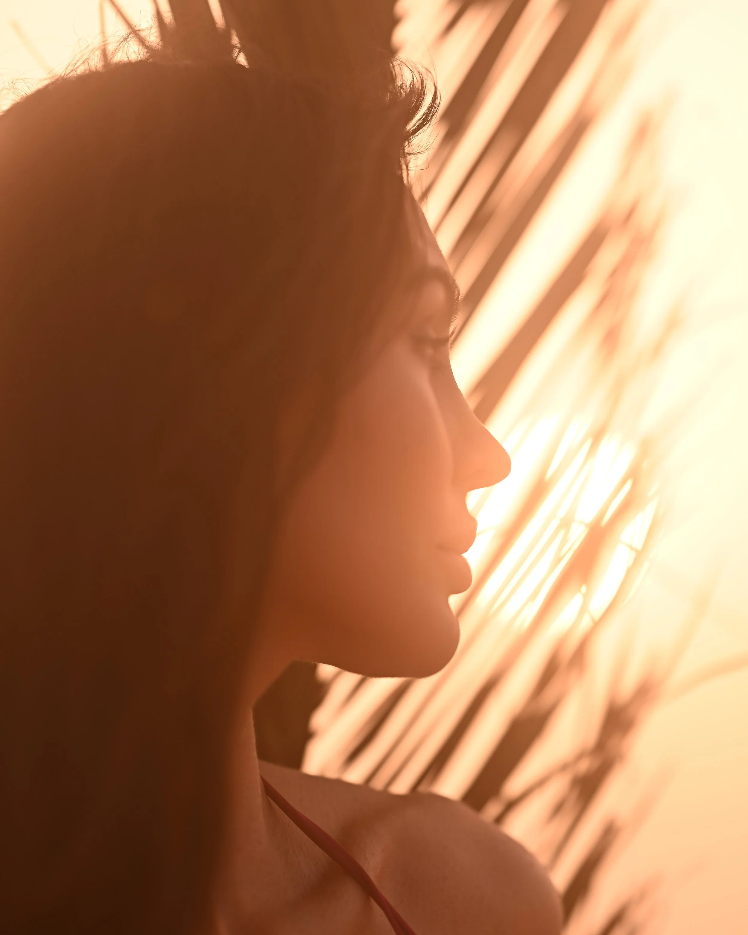 Nahaufnahme eines Menschen Profils mit Fokus auf Gesicht und Schulter, im Hintergrund goldene Beleuchtungslampen.