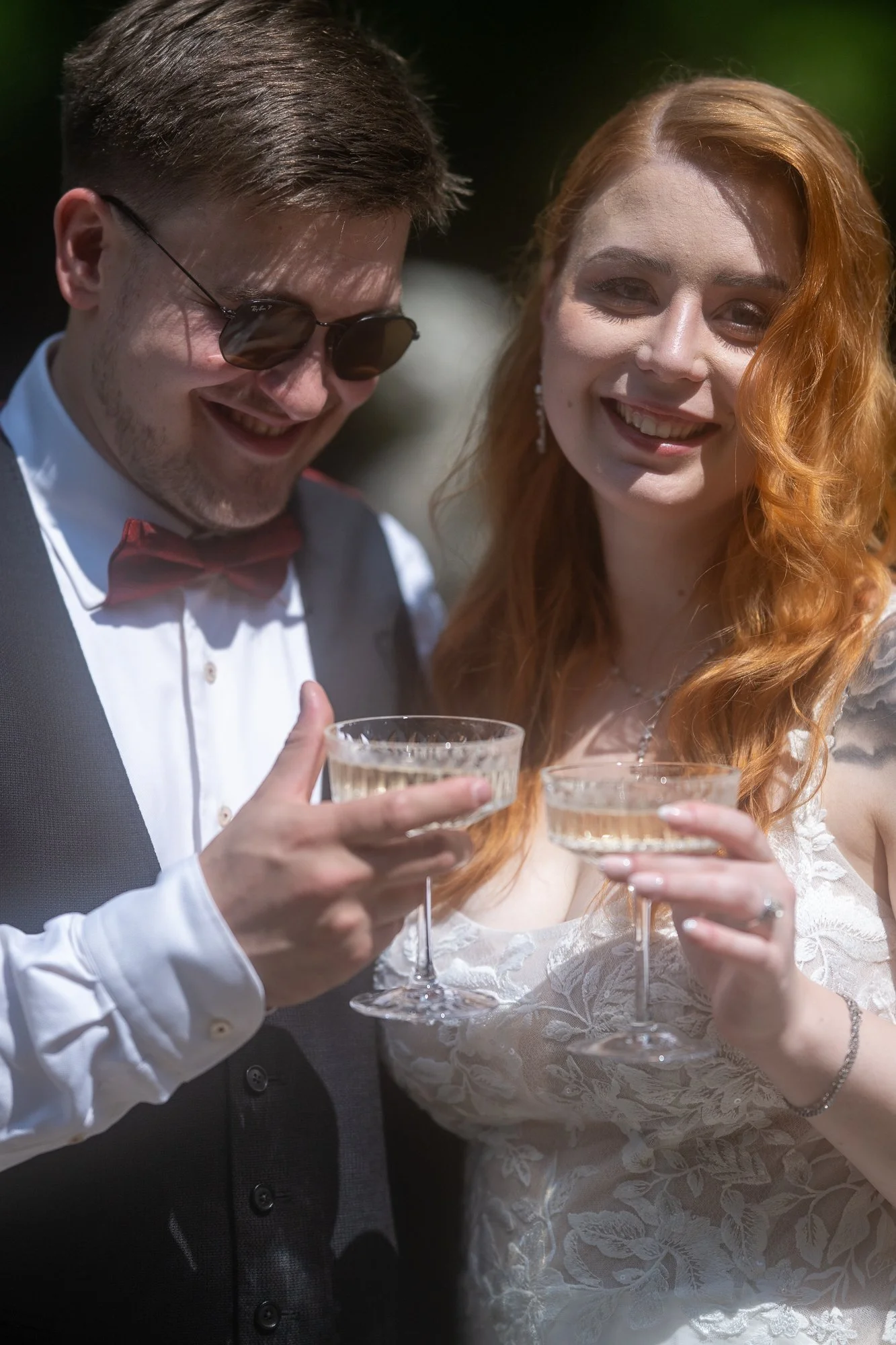 Ein junges Paar auf einer Hochzeit, das mit Champagner anstößt und lächelt.