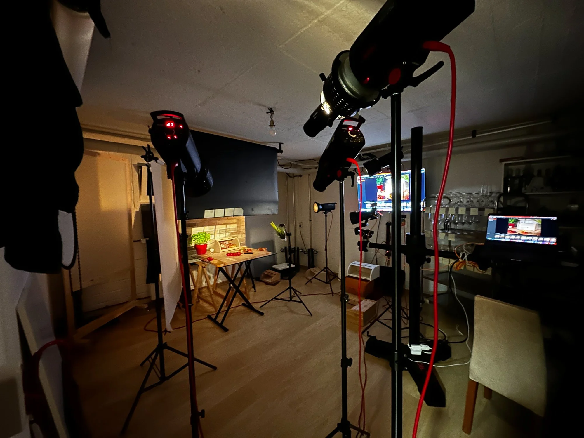 Aufnahme eines Fotostudios mit professionellem Equipment, einschließlich Studiobeleuchtung, Monitoren und Kamera, für eine Fotosession.