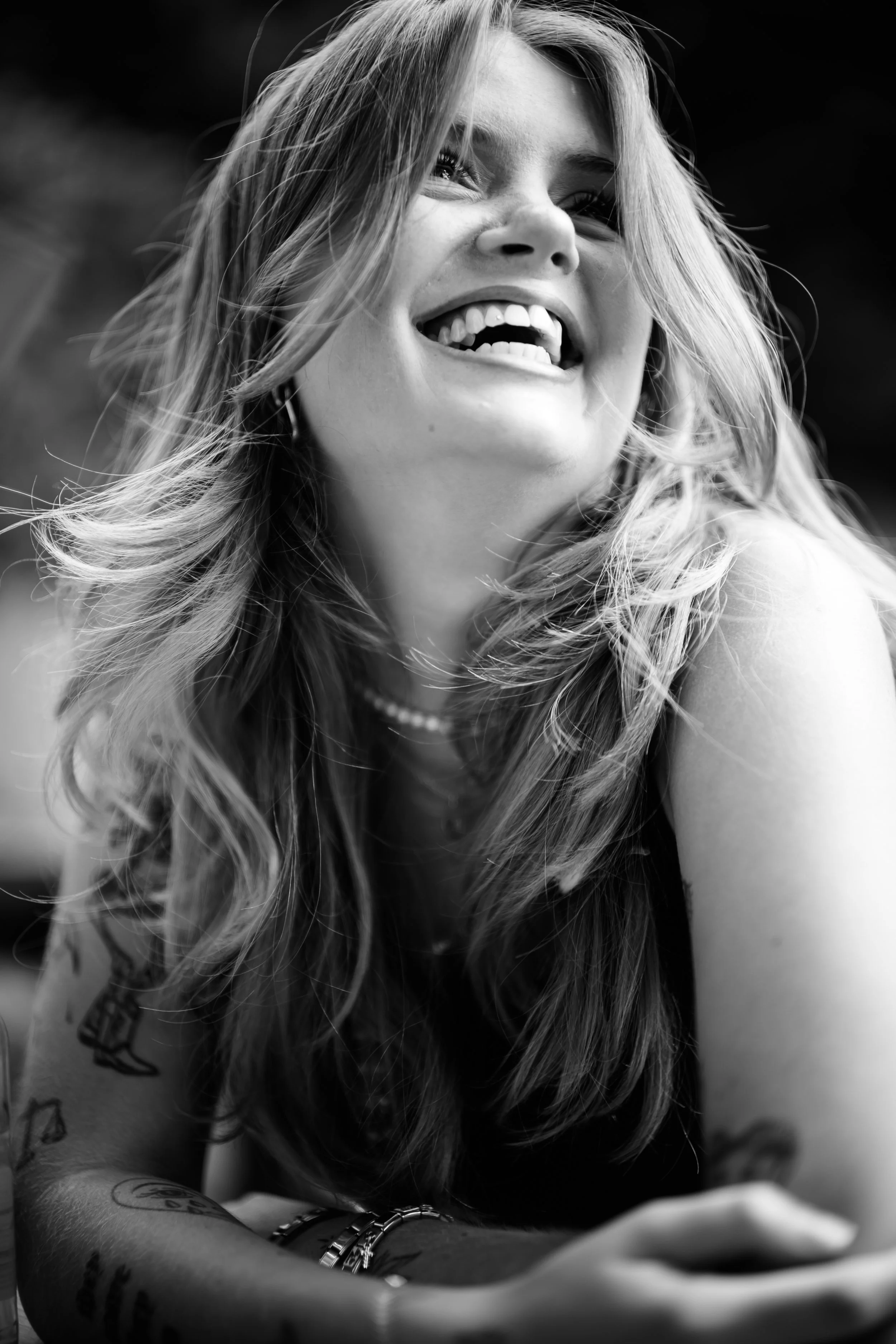 Schwarz-Weiß-Foto eines lachenden jungen Mädchens mit langen, lockigen Haaren, das nach oben schaut.