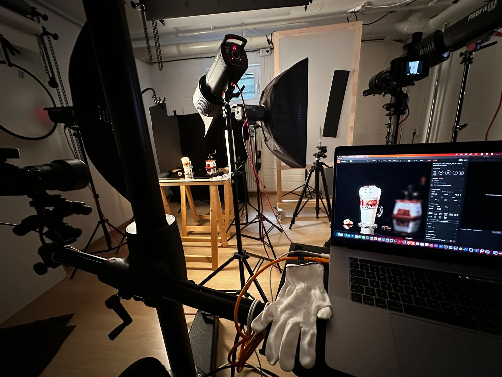 Dreharbeiten-Setup mit Kamera, Beleuchtung, Monitore und Laptop im Raum.