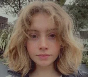 Close-up of a young woman with wavy blonde hair outdoors