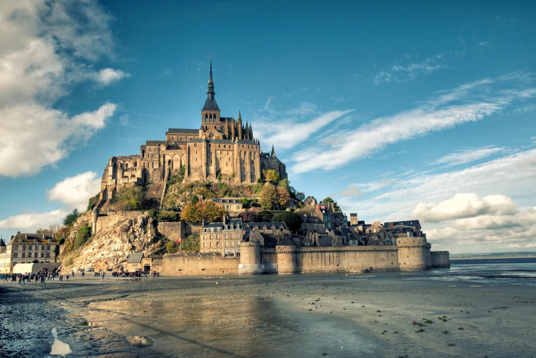 View of the historic Mont-Saint-Michel abbey and surrounding medieval buildings rising above the tidal flats in Normandy, France.