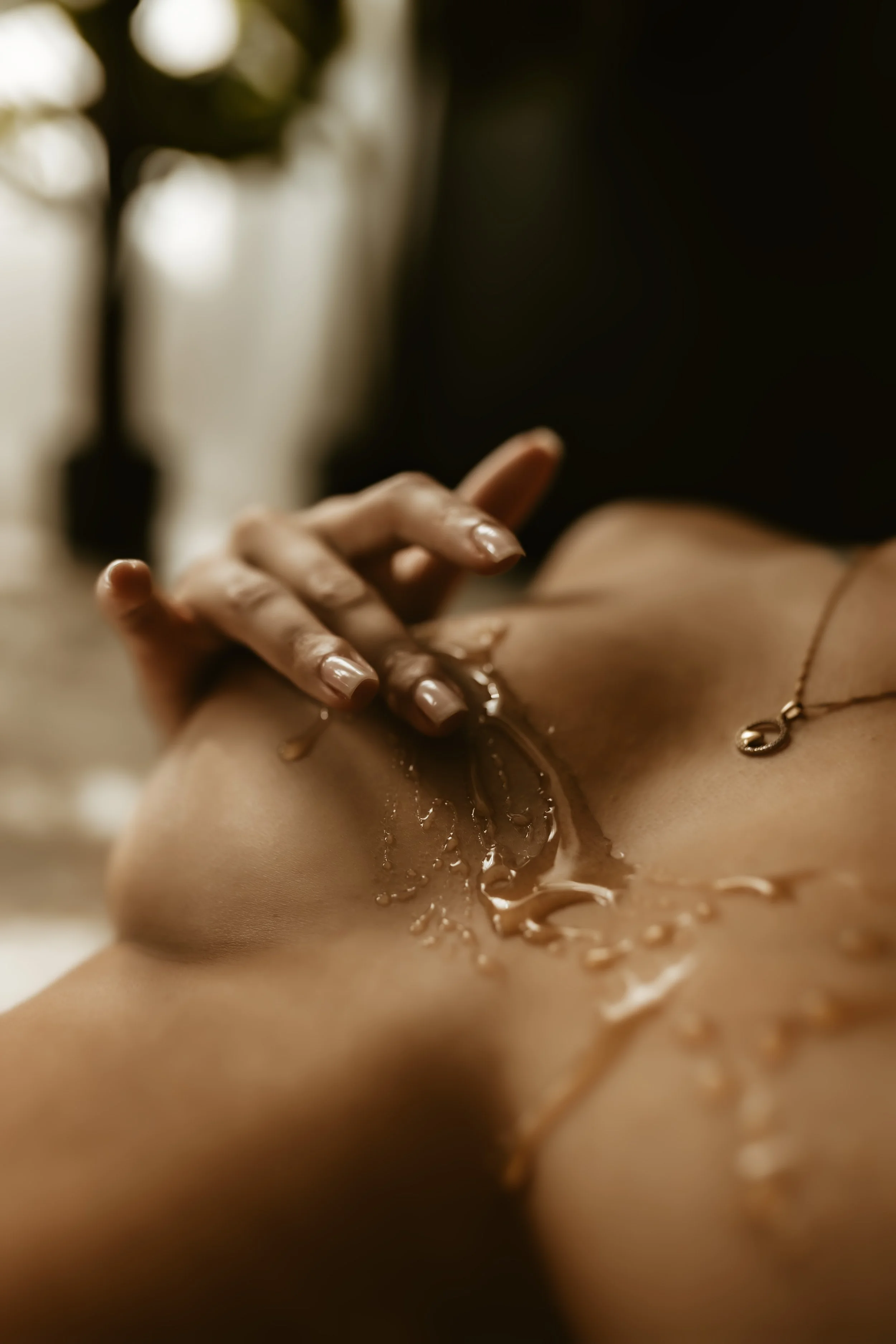 A person receiving a massage, with oil being applied to their back.