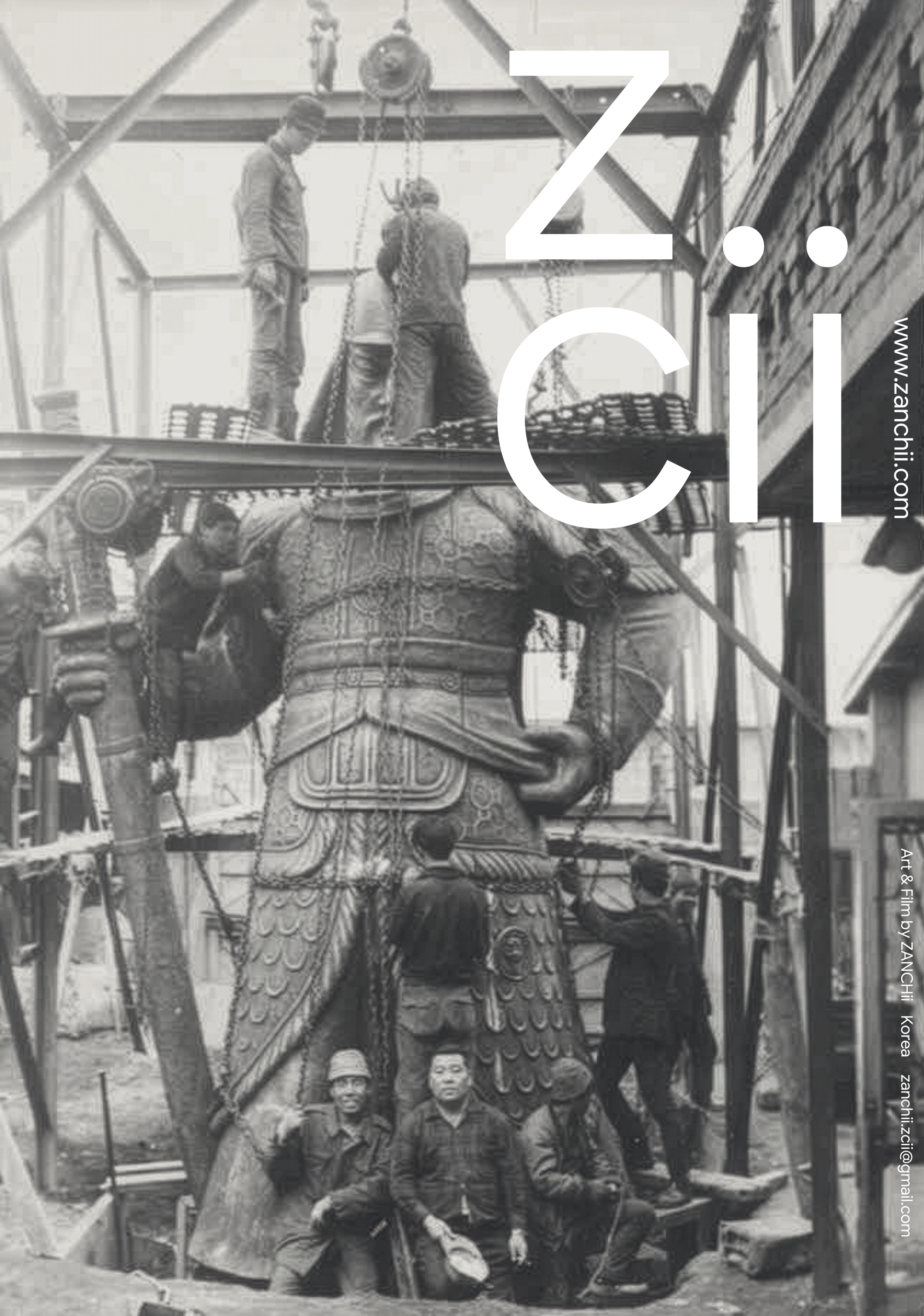Photo of a large, ornate statue being worked on by four men at a construction site with scaffolding and a brick building in the background.