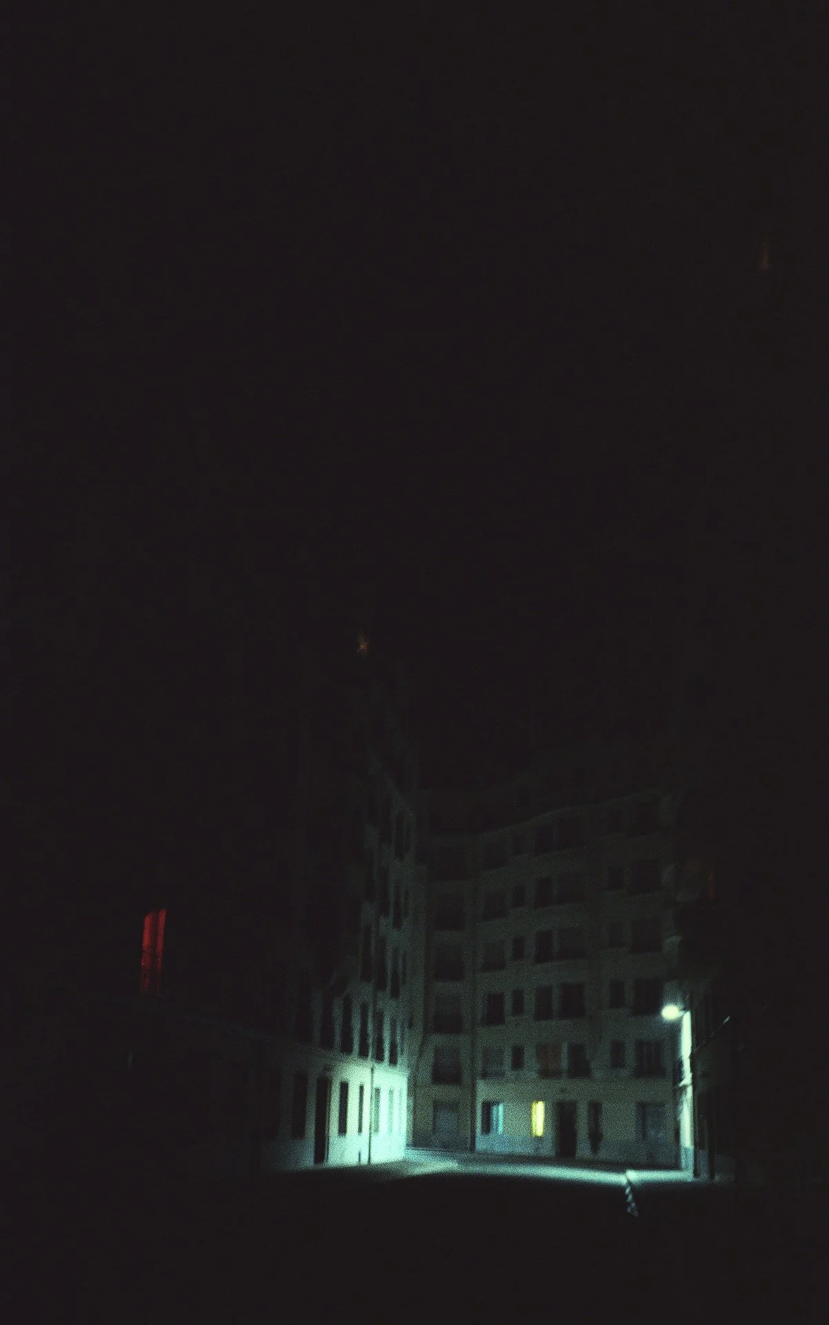 Nighttime view of a multi-story apartment building with illuminated windows and a dark sky.