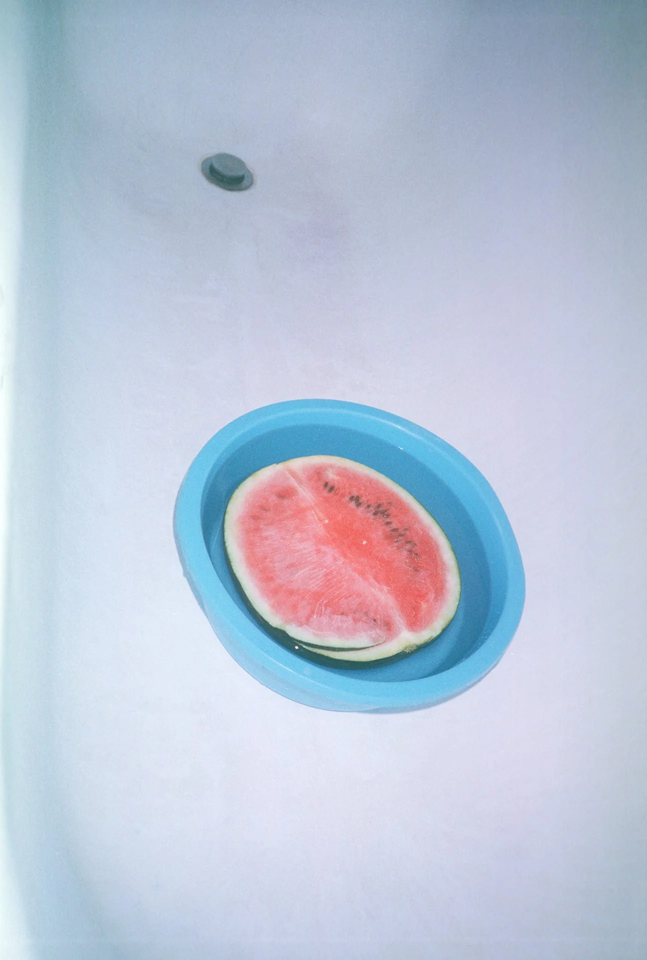 A slice of watermelon on a blue plate against a light-colored background.
