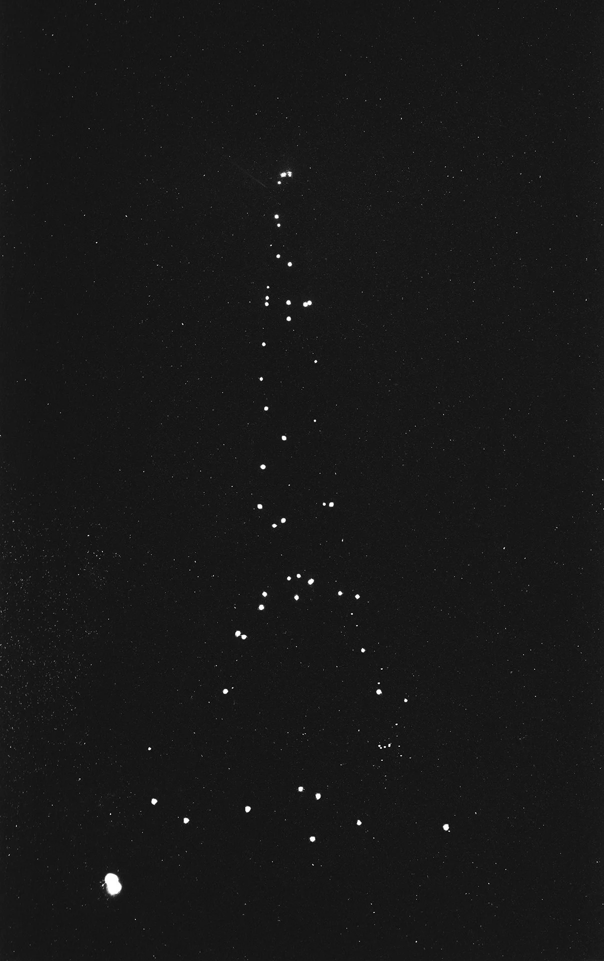 Night sky with numerous stars, including a bright cluster forming a diagonal line.