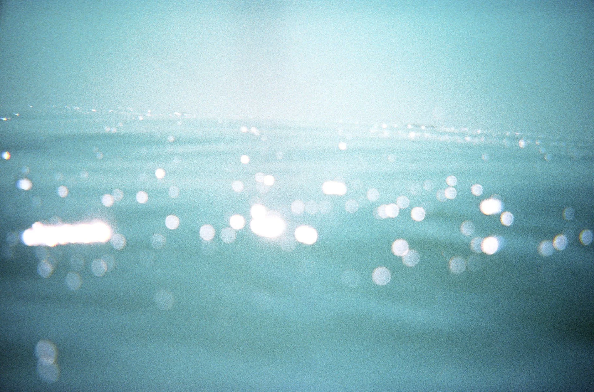 Sunlight reflecting on water surface creating bright bokeh effect.