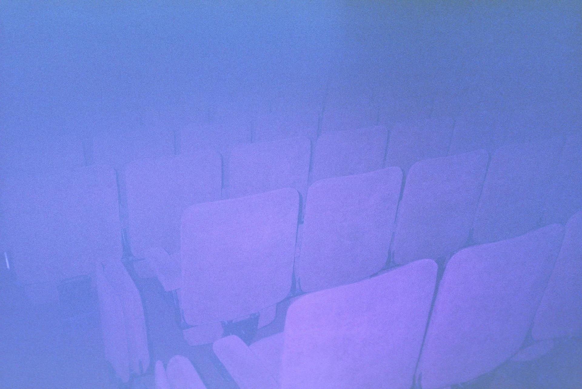 Projection of chairs on a textured wall with purple and blue lighting.