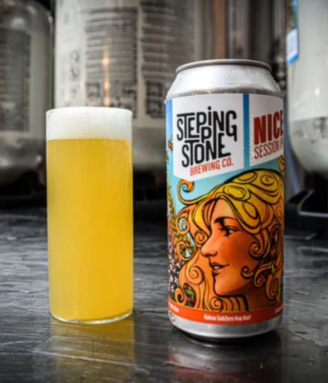 A can of Sleeping Stone Brewing Co. beer next to a glass filled with a yellow beer on a dark wooden surface.