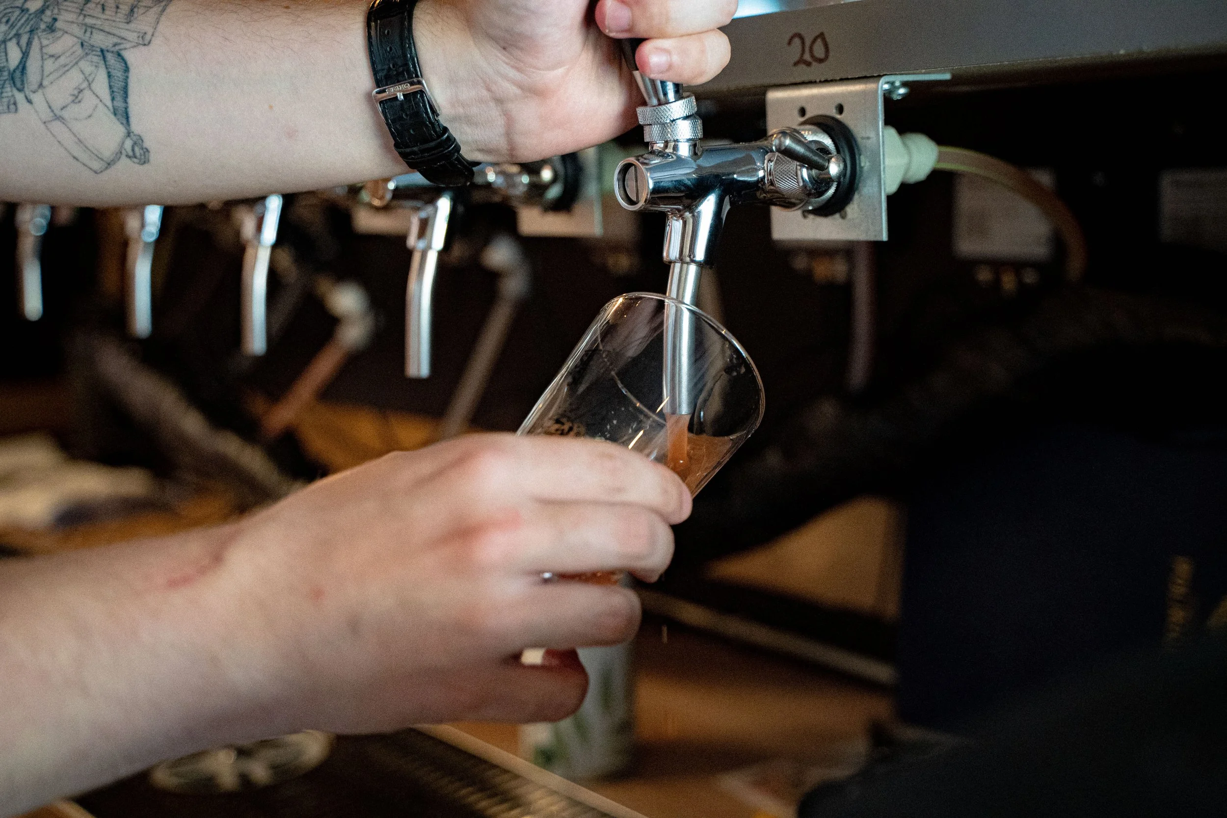 Alexander Zinck hælder øl fra taphane i glas, på Stepping Stone Kolding bar
