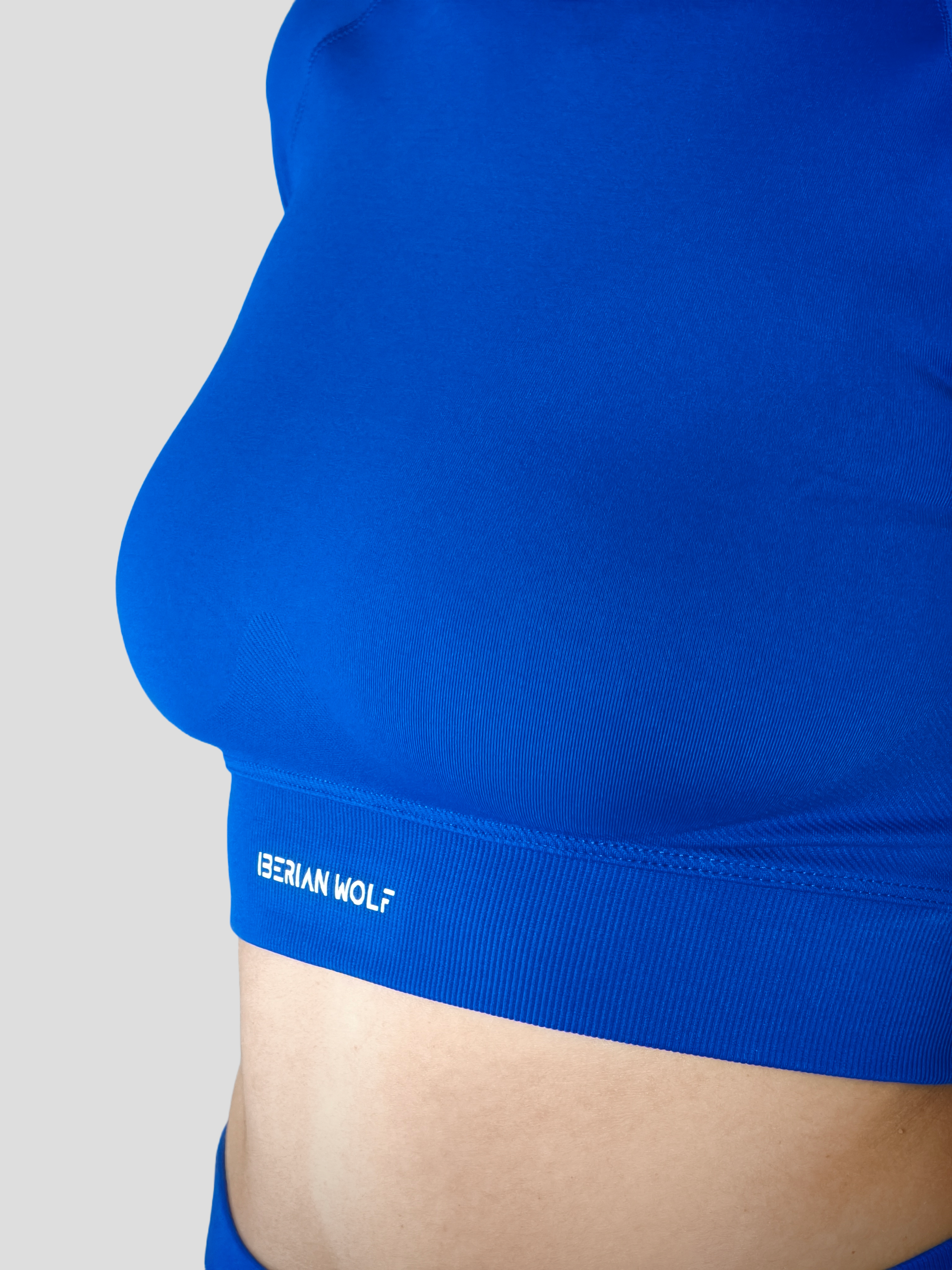 Close-up of a person's side torso wearing a blue athletic shirt with the text 'IBERIAN WOLF' visible on the shirt's hem.