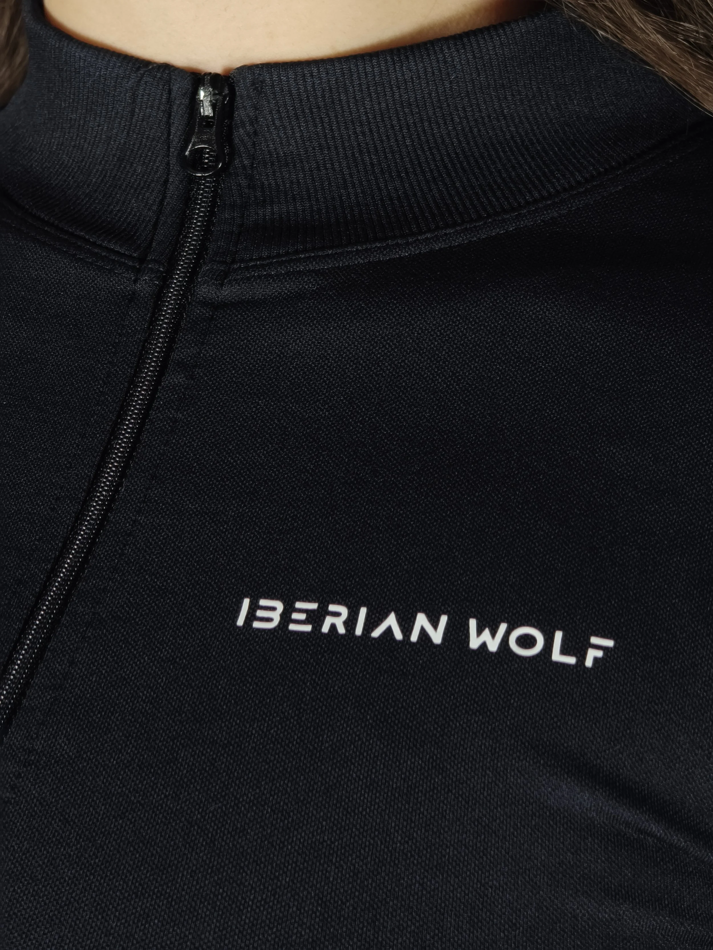 Close-up of a black jacket with a zipper and partial white text reading '13ERIAN WOLF'.