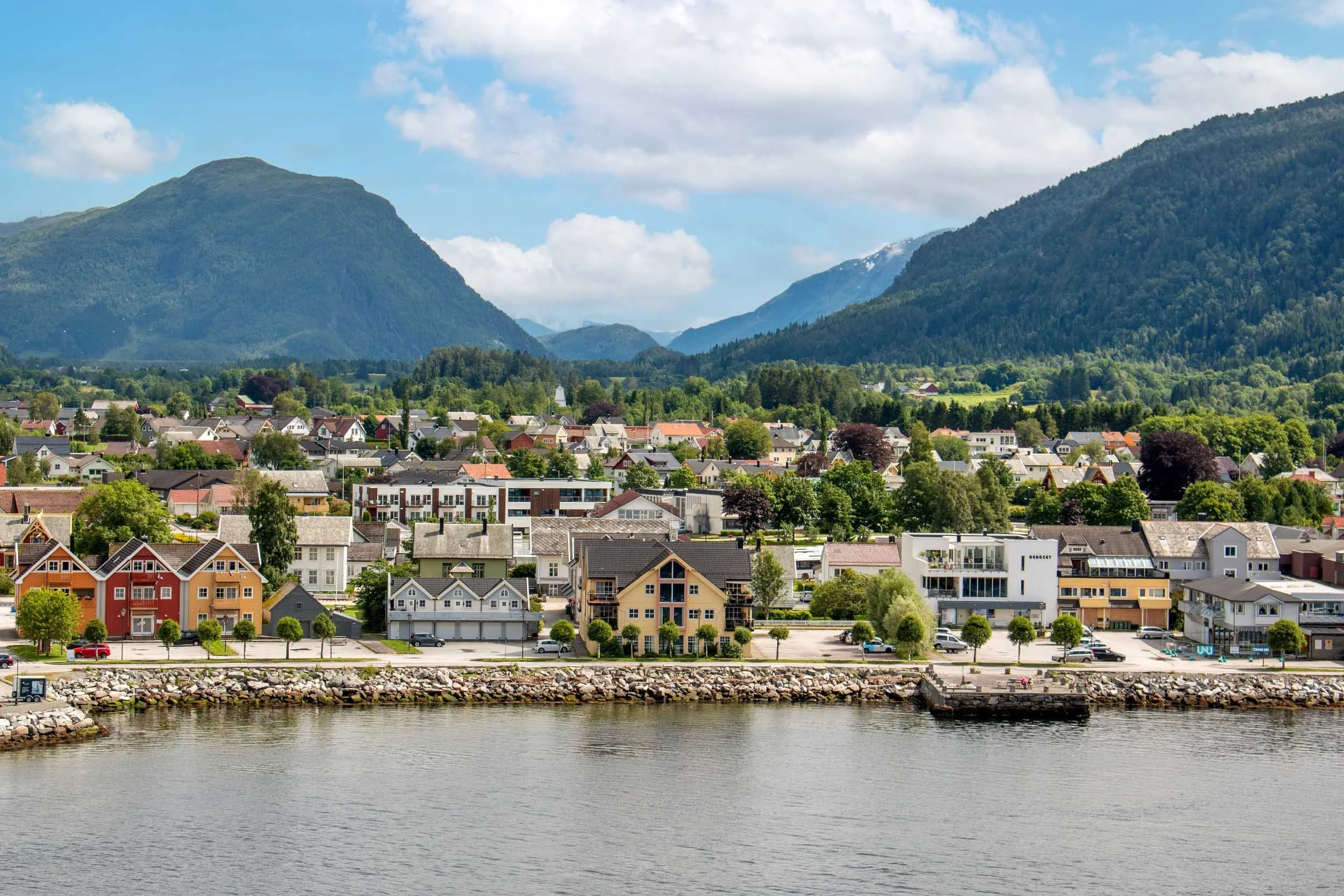 Bygd med hus foran fjell og vann i Norge.