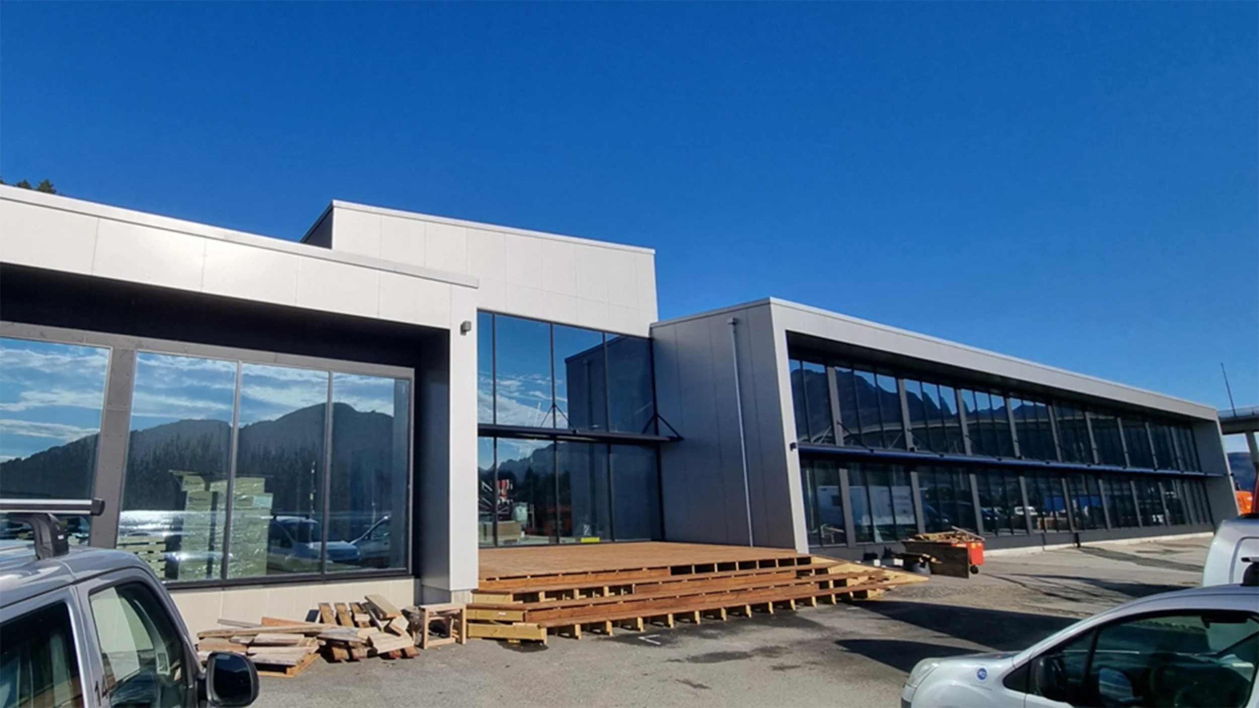 Nytt moderne bygg under konstruksjon med store glassvinduer og en klar blå himmel.