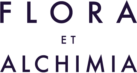 Text reading "Flora et Alchima" in dark purple on a black background.
