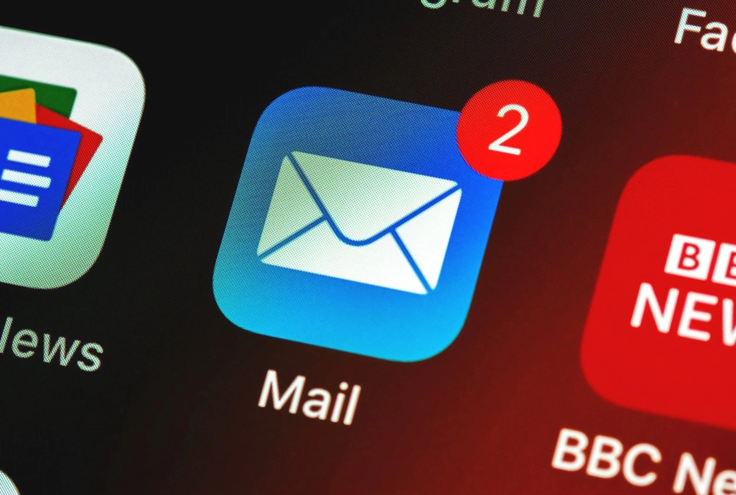Smartphone-Display mit E-Mail-App, die eine Benachrichtigung mit der Zahl 2 zeigt, neben mehreren App-Symbolen.