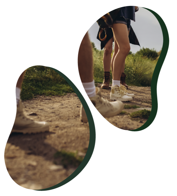 Group of people standing outdoors on a dirt path, wearing shorts and sneakers, with greenery in the background.