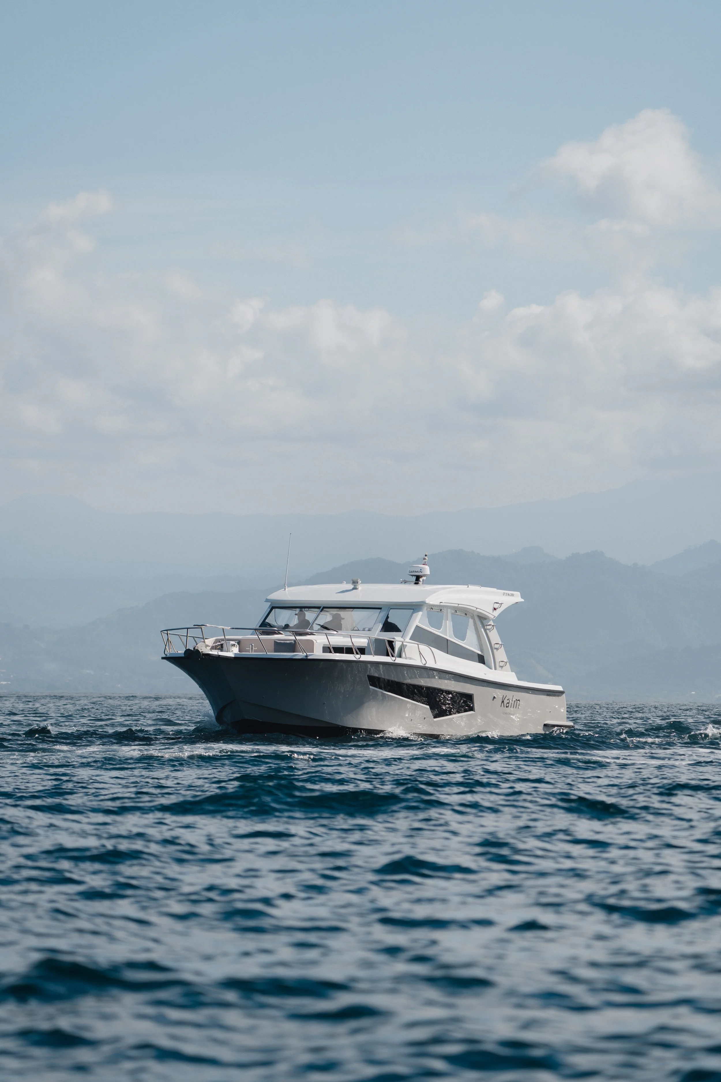Side profile of the Kalm Charters vessel cruising on open water.