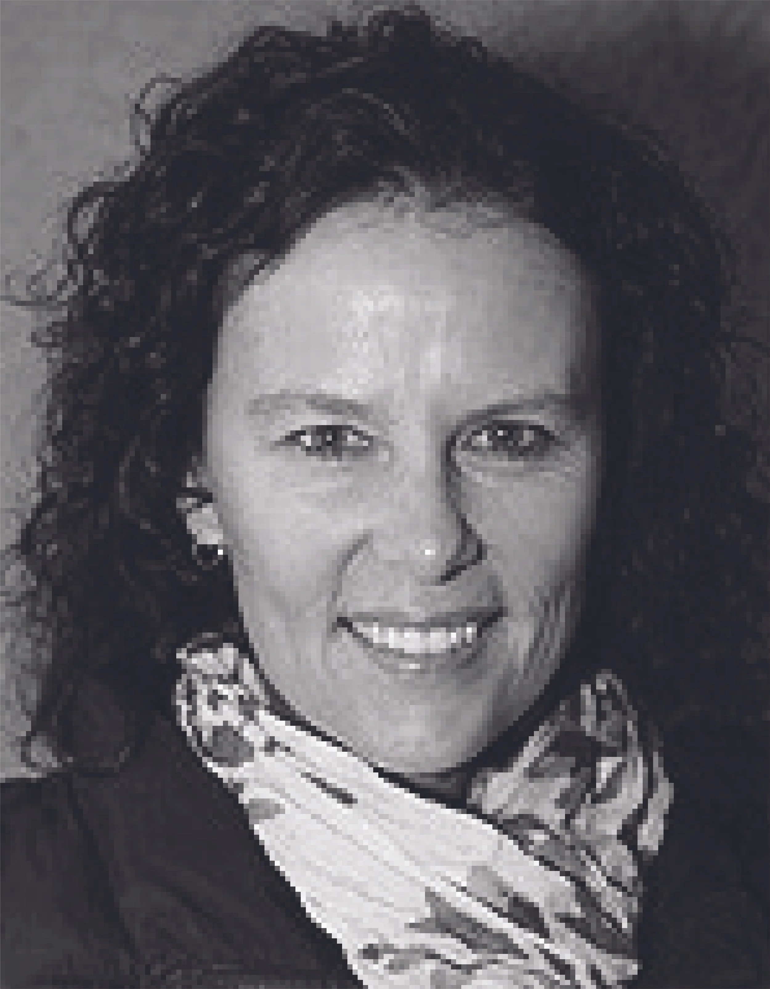 Black and white portrait of a smiling woman with curly dark hair, wearing a patterned scarf.