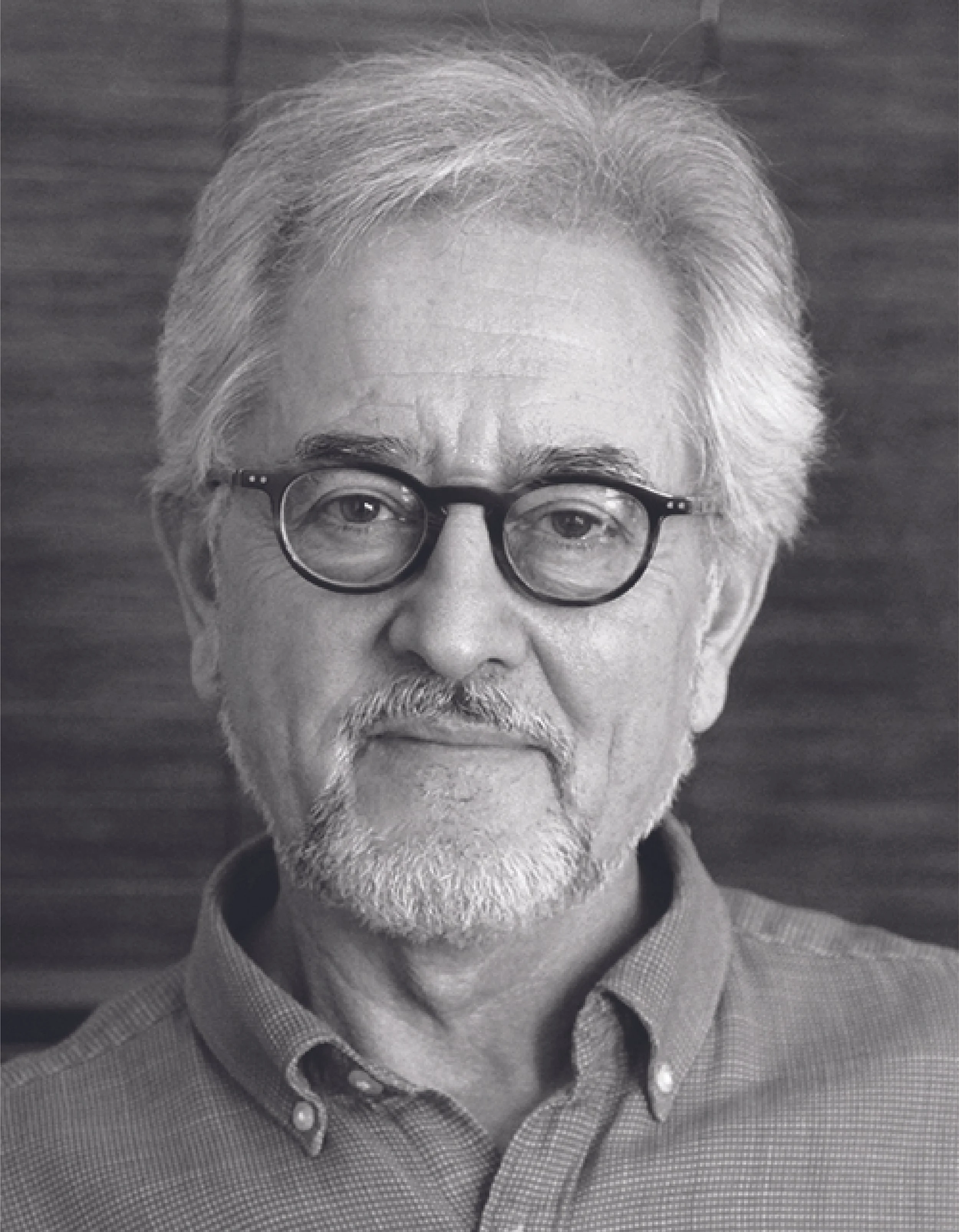 Close-up black and white portrait of an elderly man with gray hair, beard, glasses, and wearing a button-up shirt.