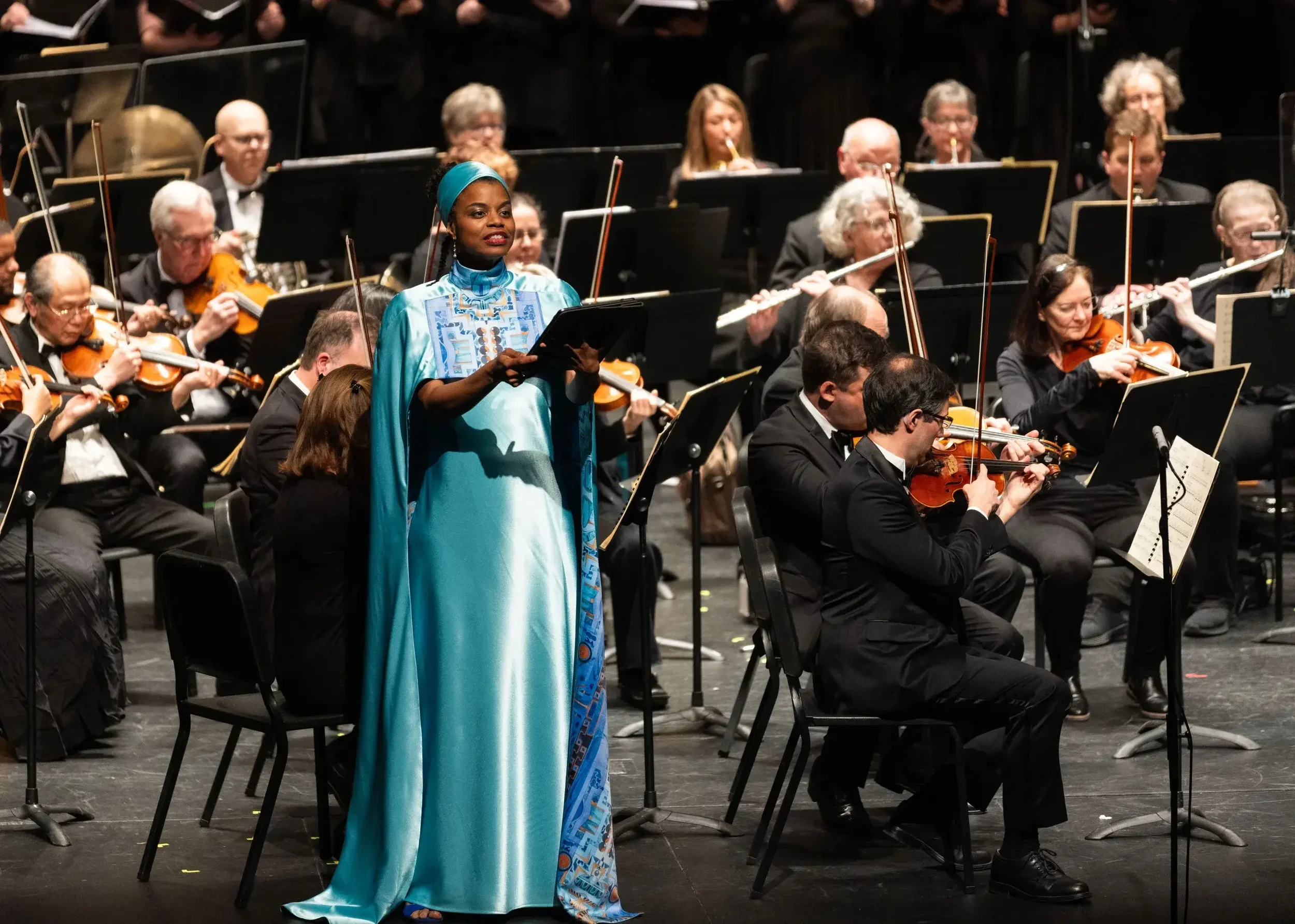 Soprano Ellaina Lewis performs with an orchestra, wearing an opera gown printed with Zahyr Lauren’s artwork. 