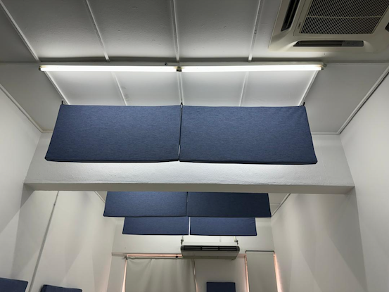 Soundproofing foam panels in a room with white walls and ceiling, blue panels on ceiling, and fluorescent lighting.