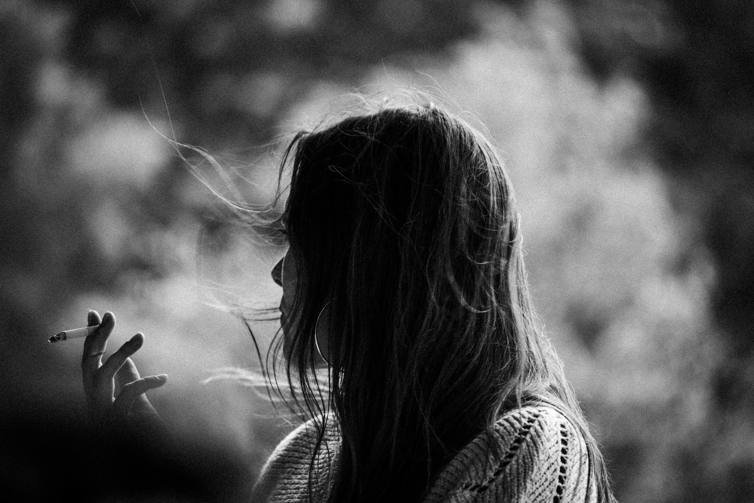 Black and white profile of a woman with hair in the wind smoking, illustrating the loss of identity when women quit smoking.
